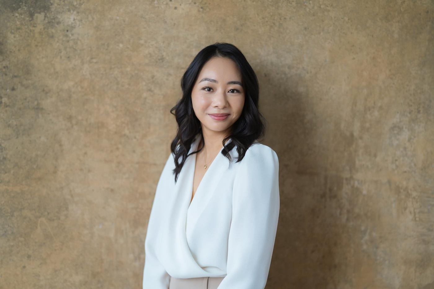 Dr. Mary Sun standing against a warm textured wall
