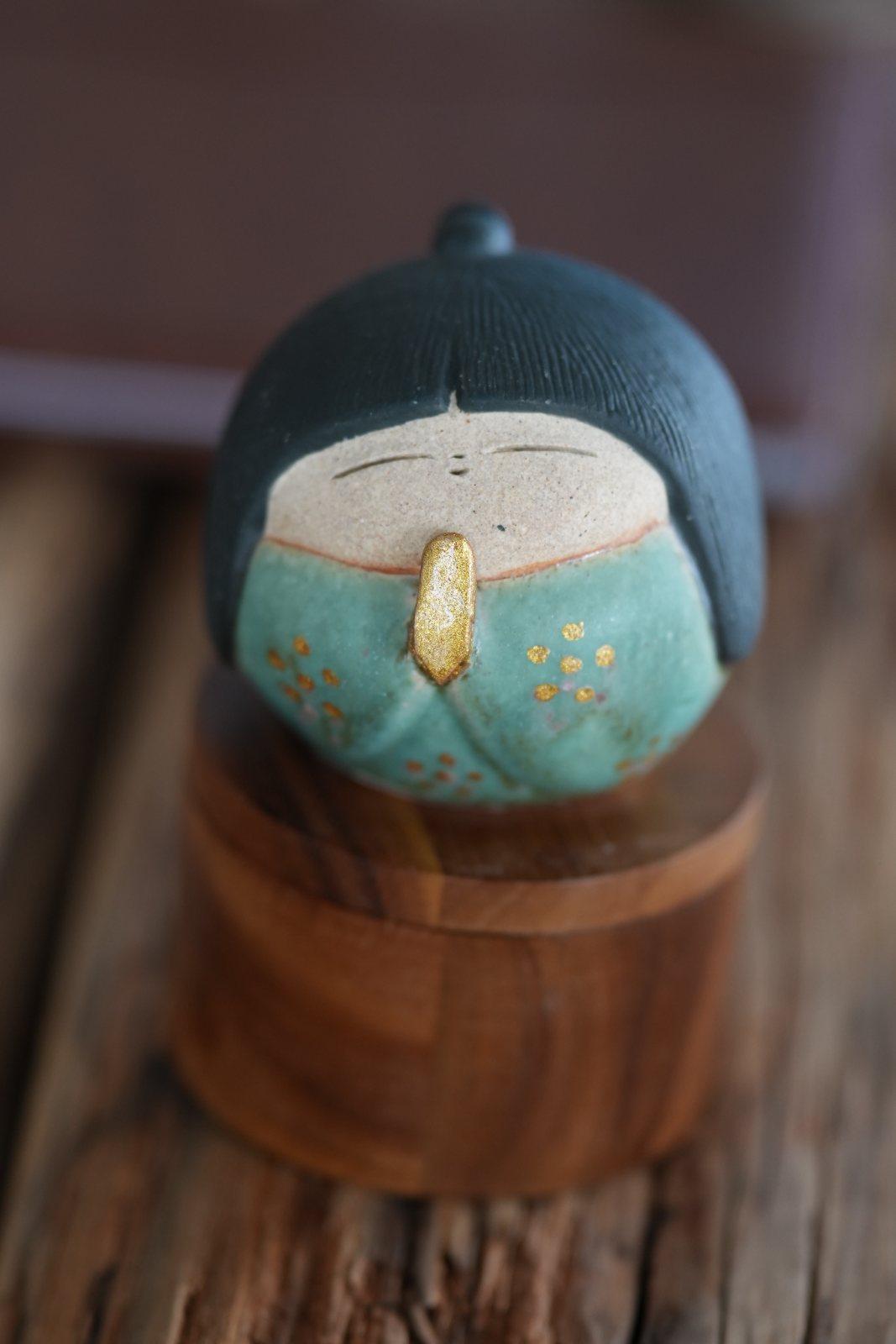 A small Japanese ceramic figure, eyes closed