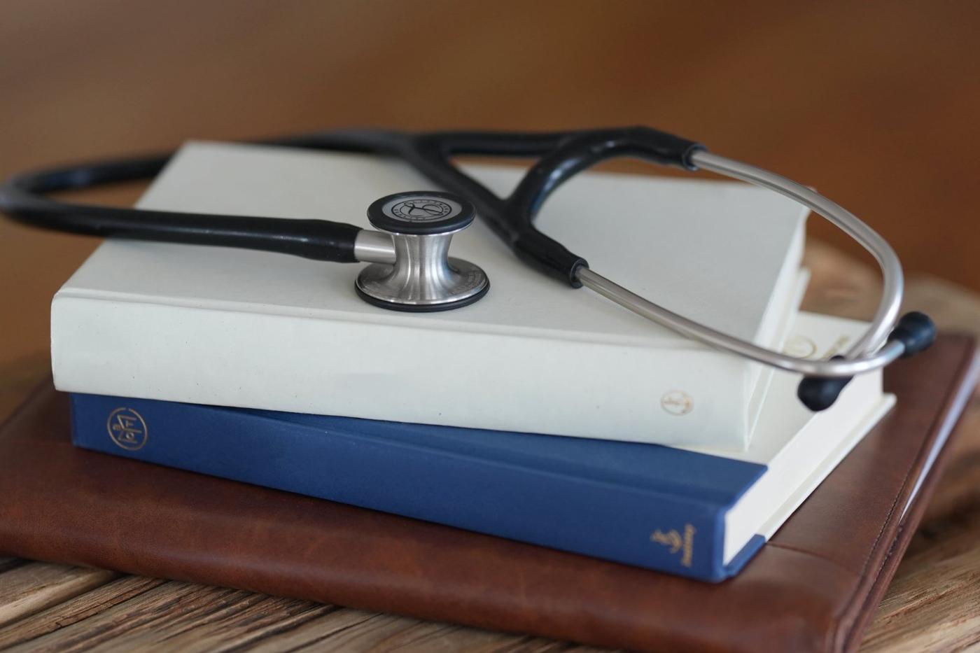 A stethoscope resting on two books and a leather padfolio